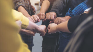group of people in a circle showing fists.